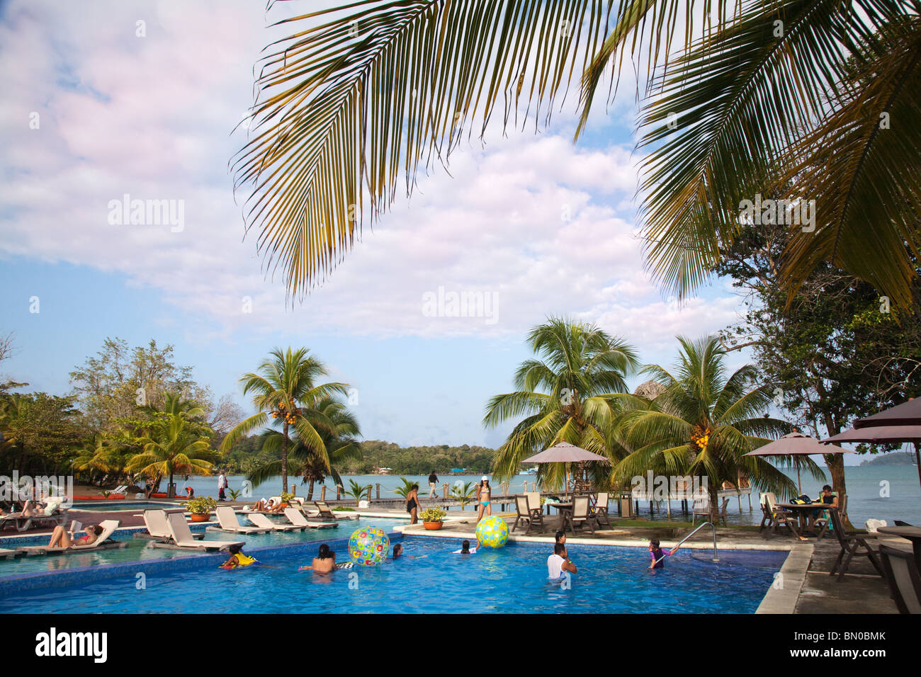 Tourists at swimming pool and view of Beach bar and Palm trees at Playa Tortuga Bocas del Toro Panama Stock Photo