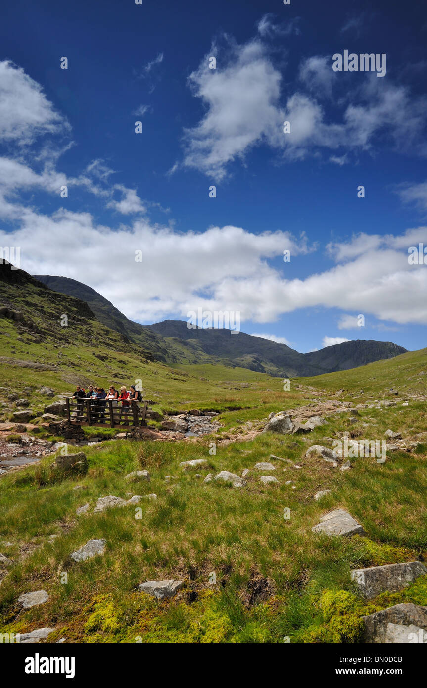 A party of walkers on a bridge over Sty Head Gill in Borrowdale in the Lake District Stock Photo