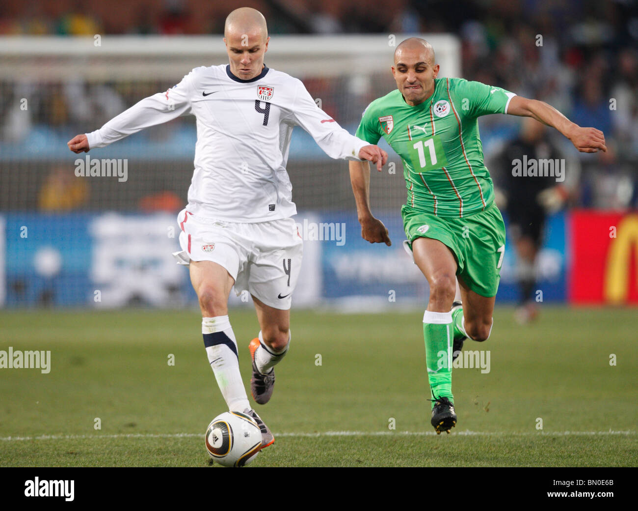 Michael Bradley of the United States (4) drives the ball against Rafik Djebbour of Algeria (11) during a 2010 World Cup match. Stock Photo