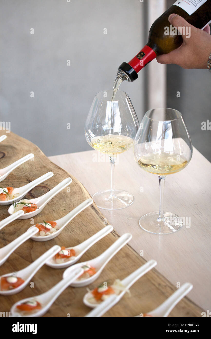 Canada,Ontario,Niagara-on-the-Lake, wine being poured into wine glasses and appetizers in foreground Stock Photo