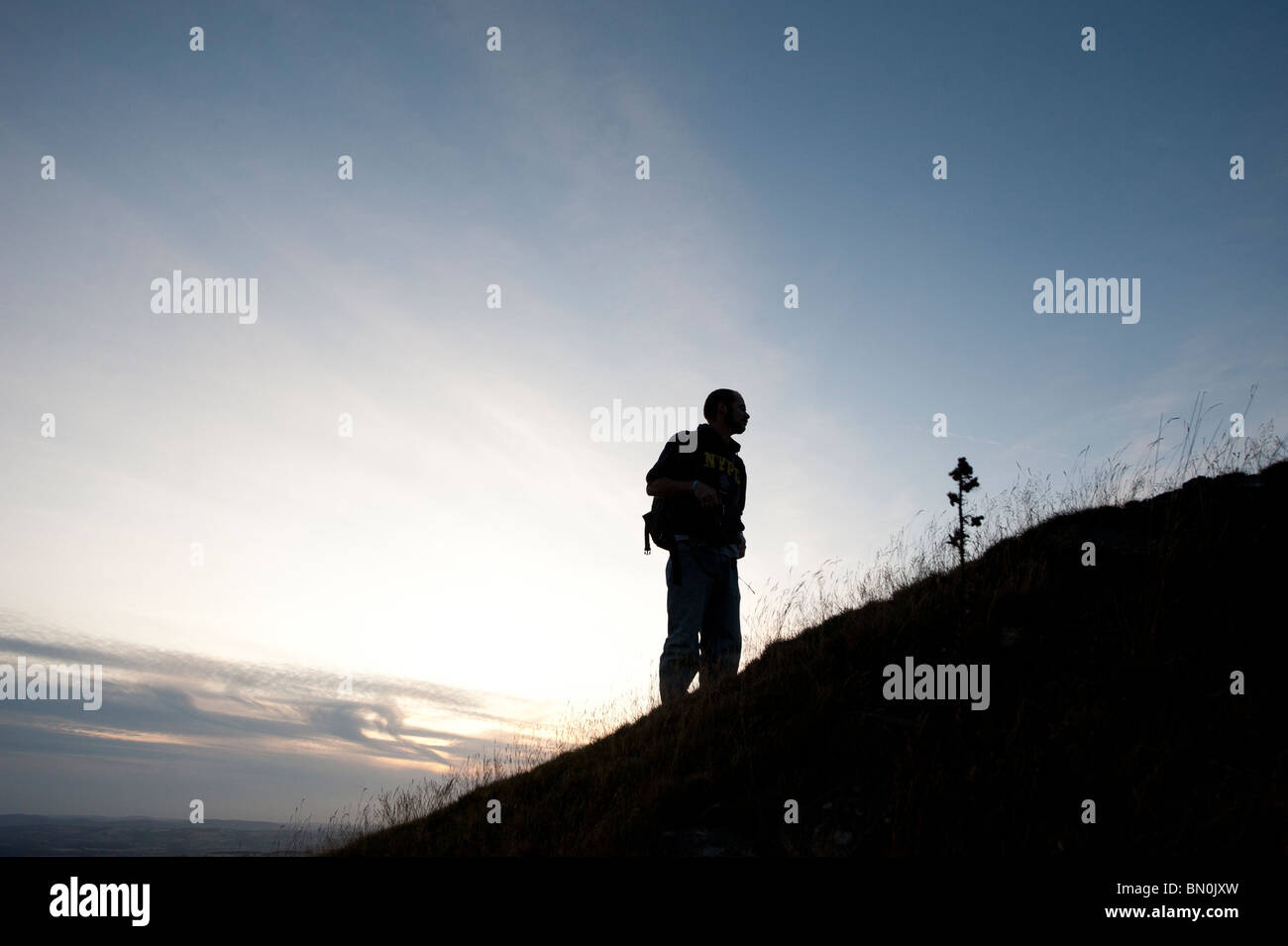 Silhouette of man stood on the side of a hill enjoying the view. Stock Photo