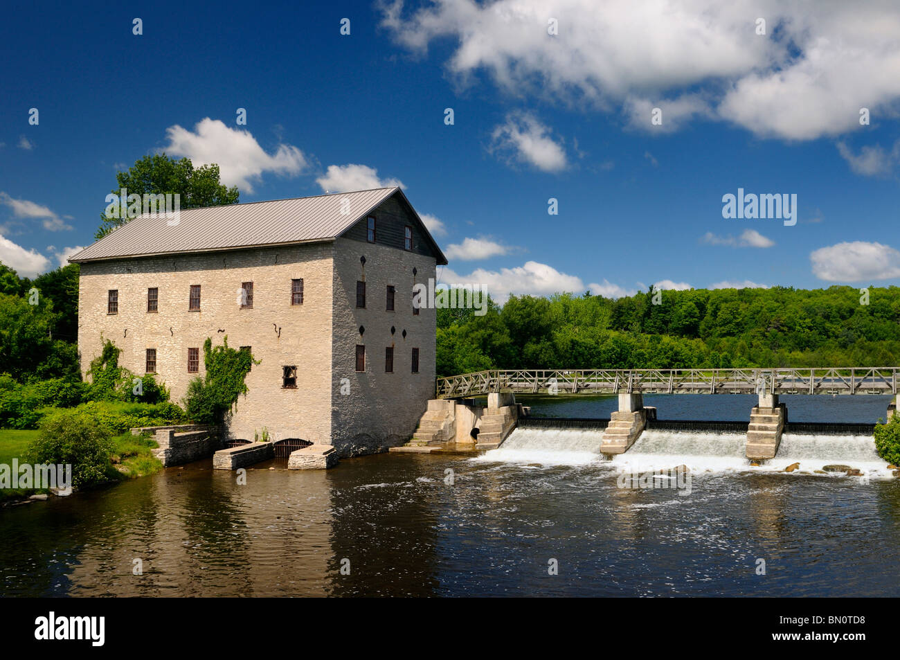 Lang Grist Mill and bridge over waterfall dam at Pioneer Village on the Indian River Ontario Keene Ontario Canada Stock Photo