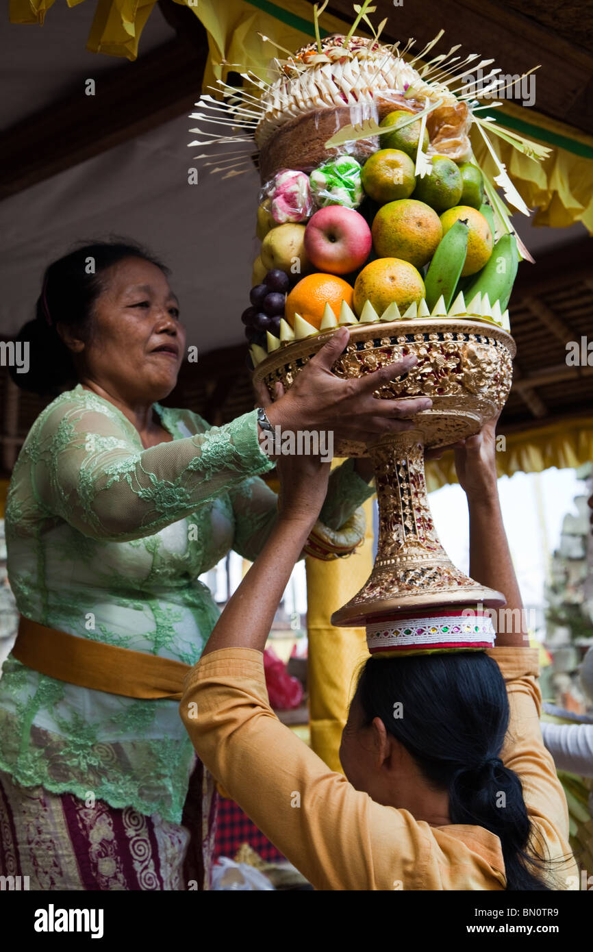 Balinese women with gebogan or arranged fruit offerings, making their way to Hindu Temple at Buda Keliwon Pegatuwakan Stock Photo