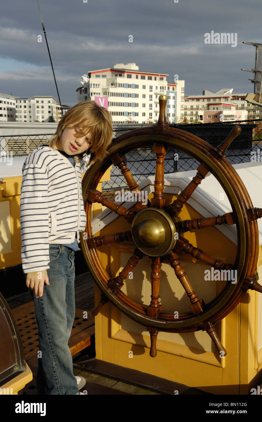 A pre-teen boy standing by the wheel on the deck of the SS Great Britain, Bristol, England. Stock Photo