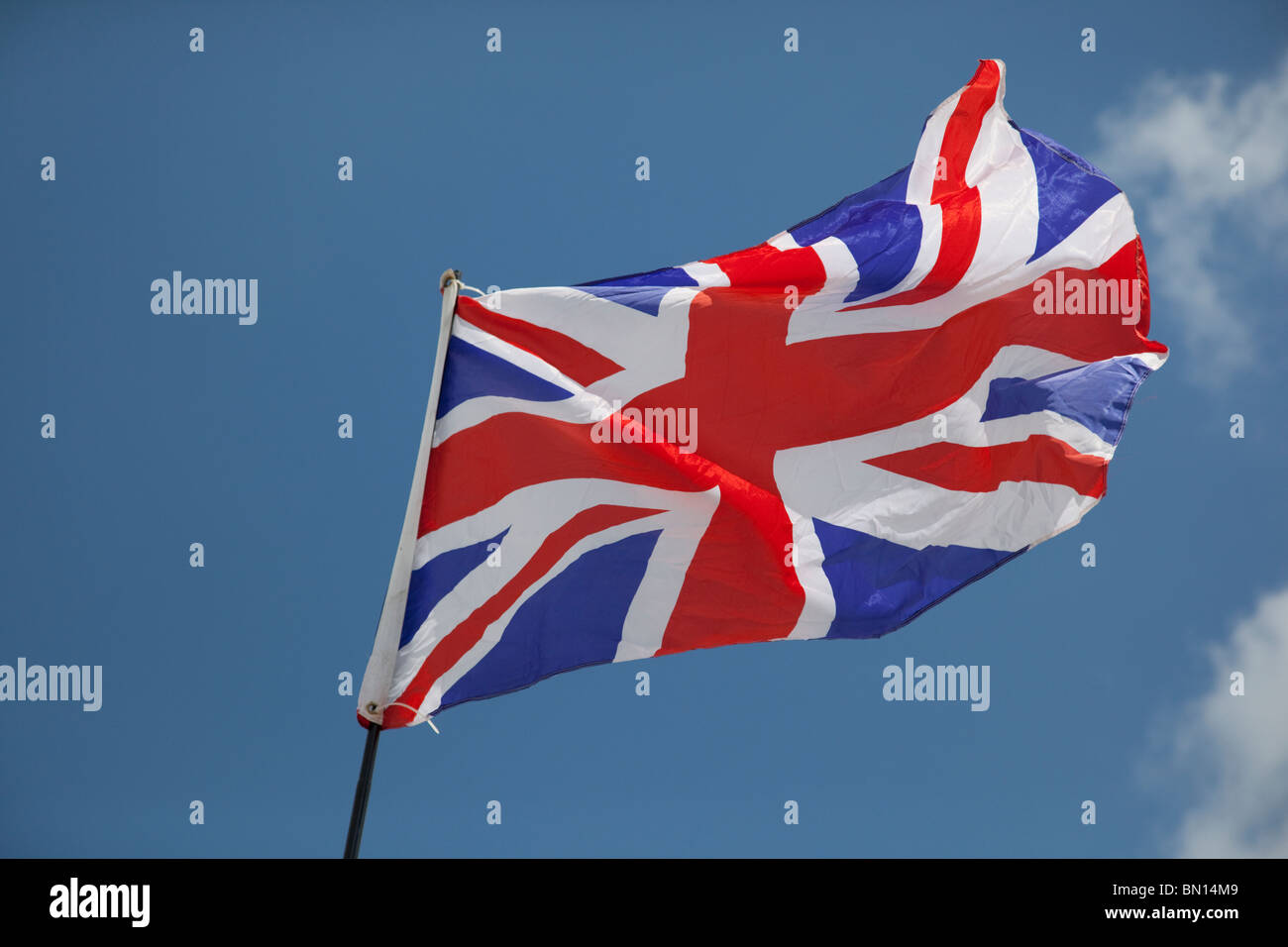 Union jack flag flying in light breeze against blue sky UK Stock Photo