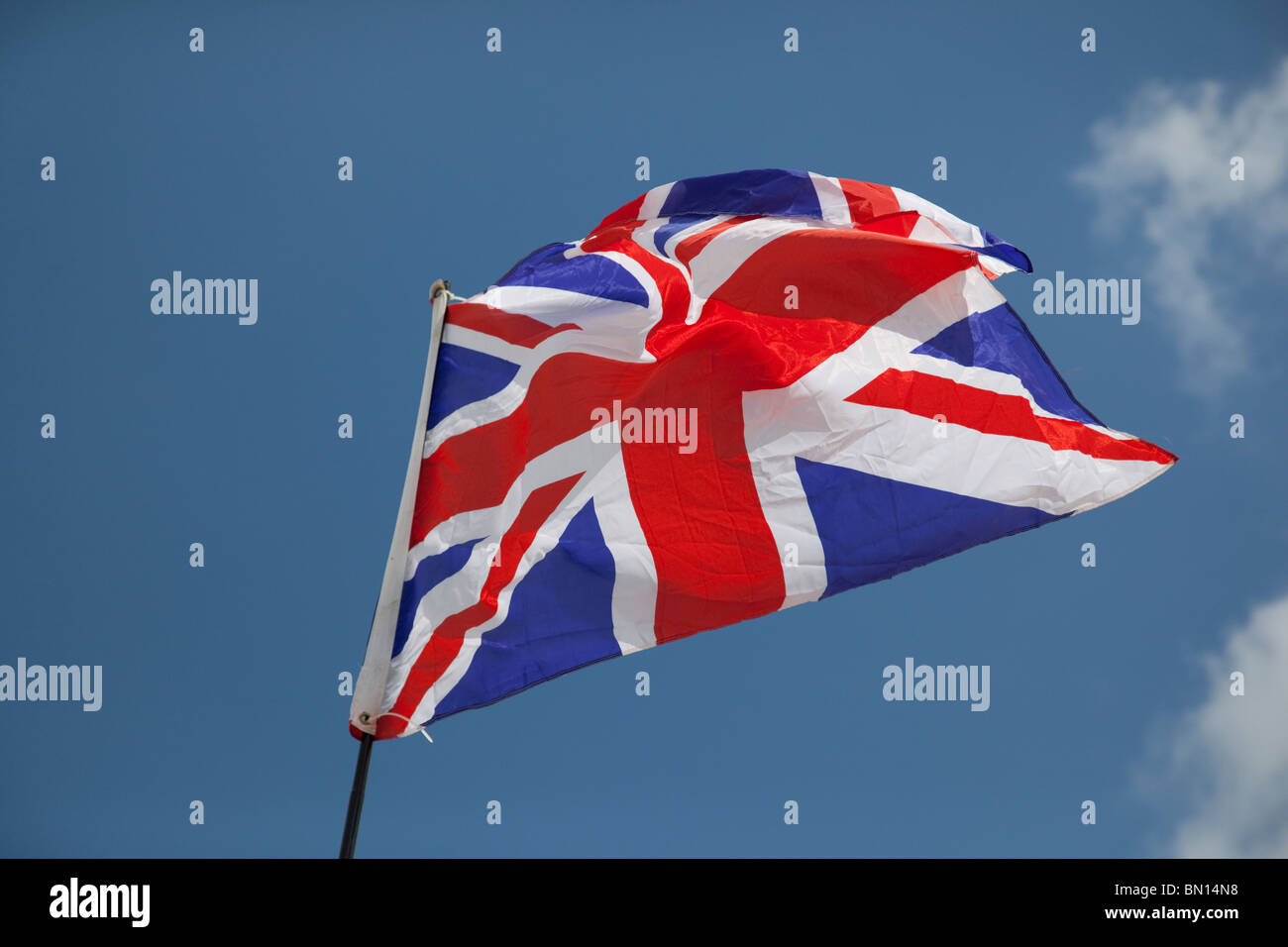 Union jack flag flying in light breeze against blue sky UK Stock Photo