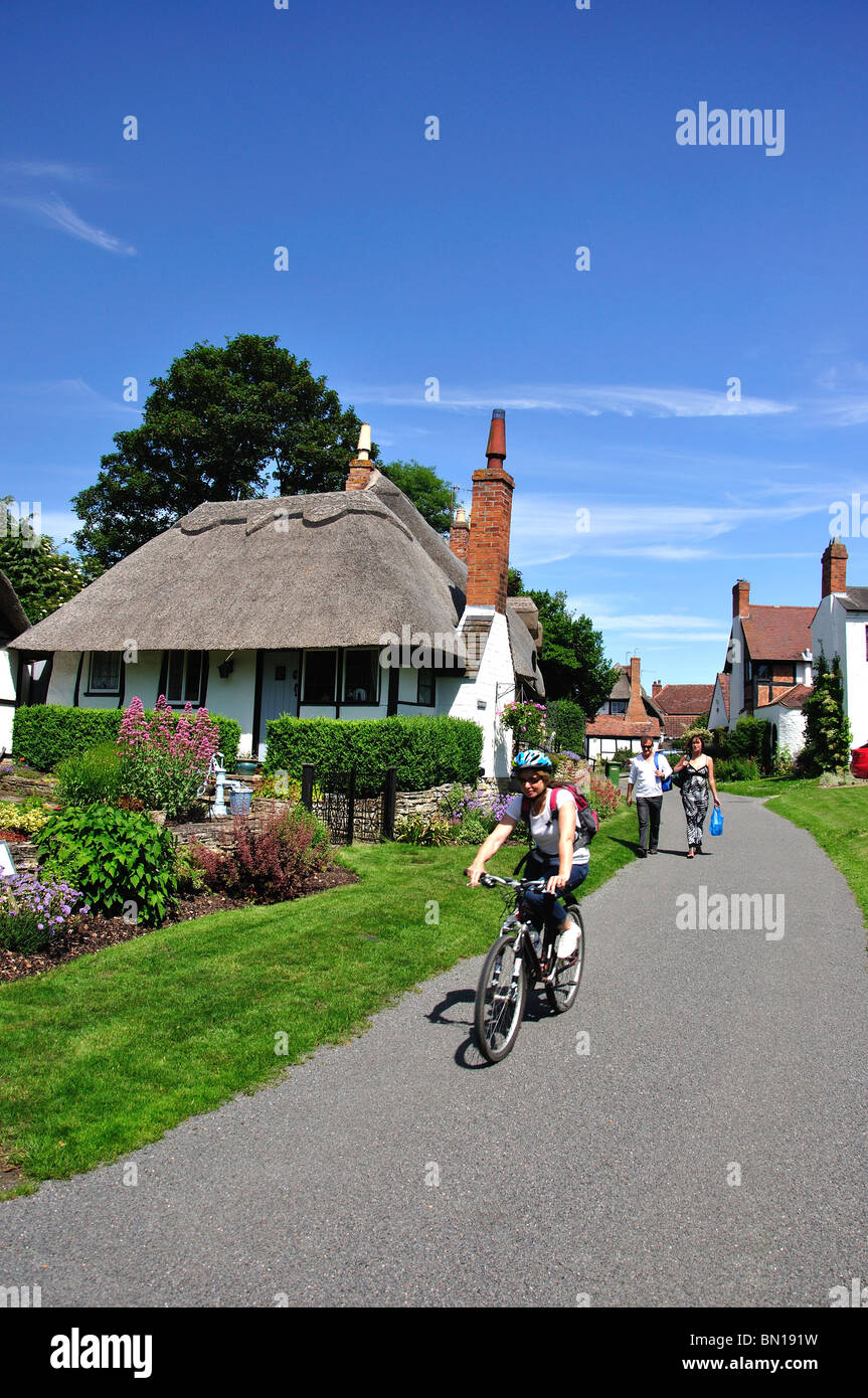 Woman cycling through village, Welford-on-Avon, Warwickshire, England, United Kingdom Stock Photo