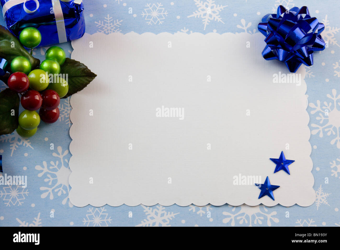blank Christmas card with blue bow, berry accent on a snowflake background with copyspace Stock Photo