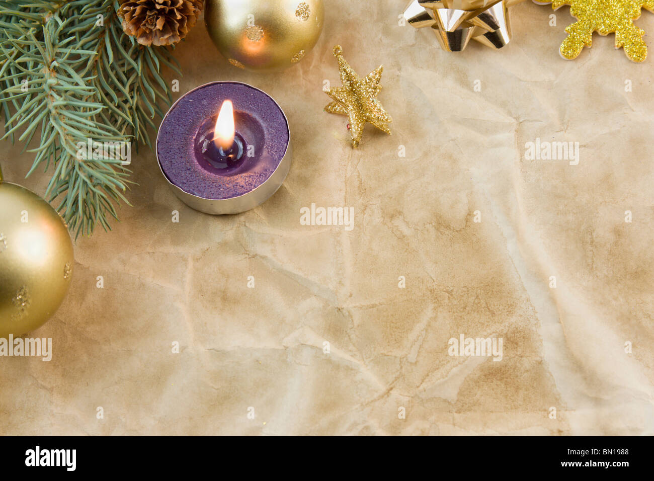 single purple tea light candle with gold christmas elements on antique paper with copyspace Stock Photo