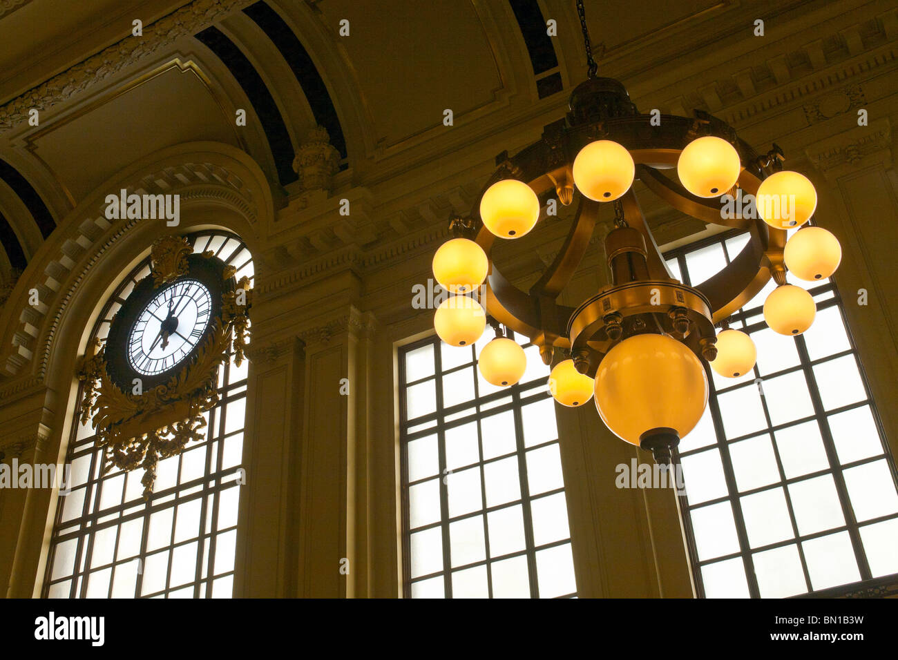 A train station clock and light fixture. Stock Photo