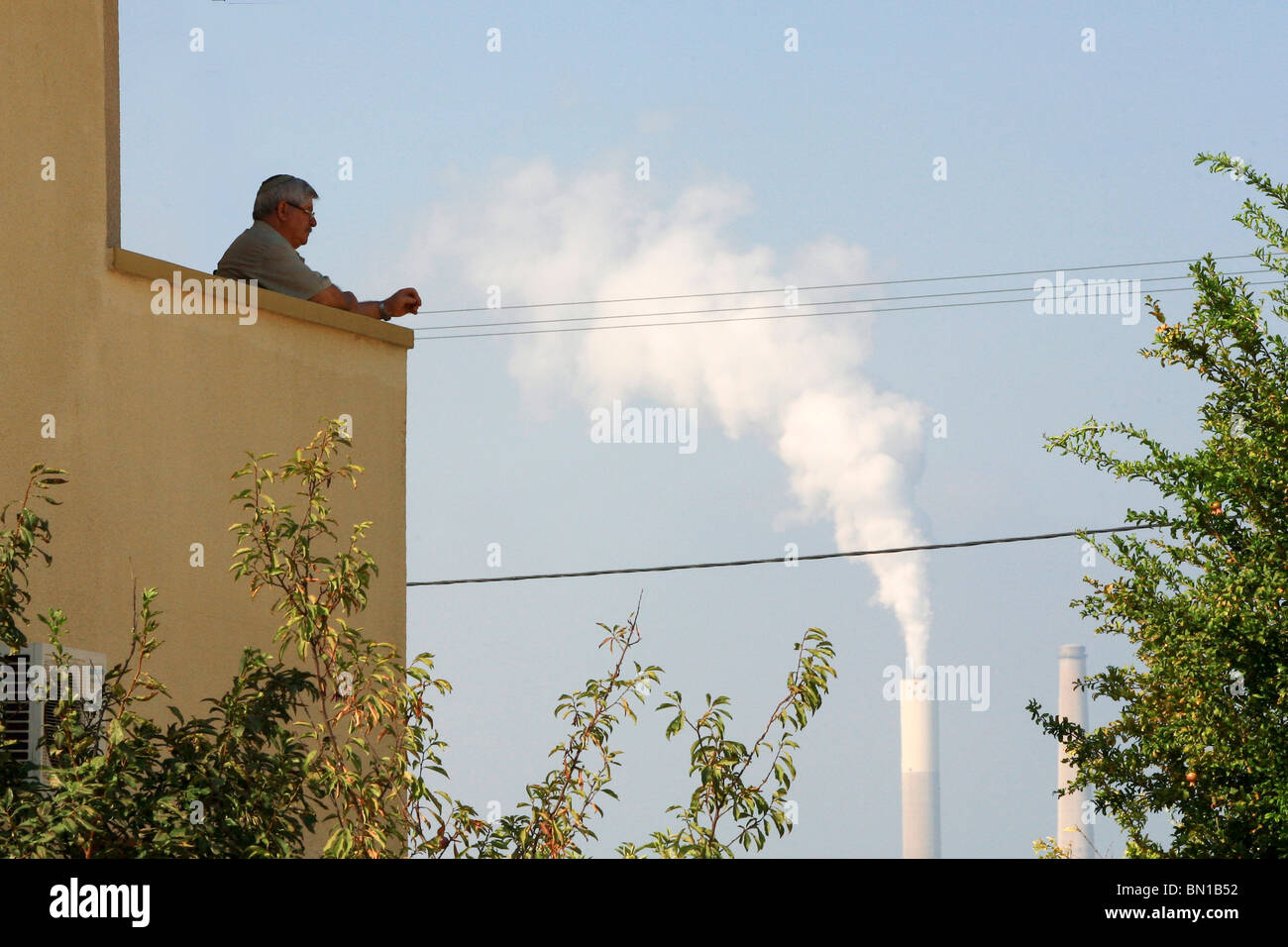 Israel, Hadera, The smoke emitting coal operated power plant's flues as seen from a residence's home Stock Photo