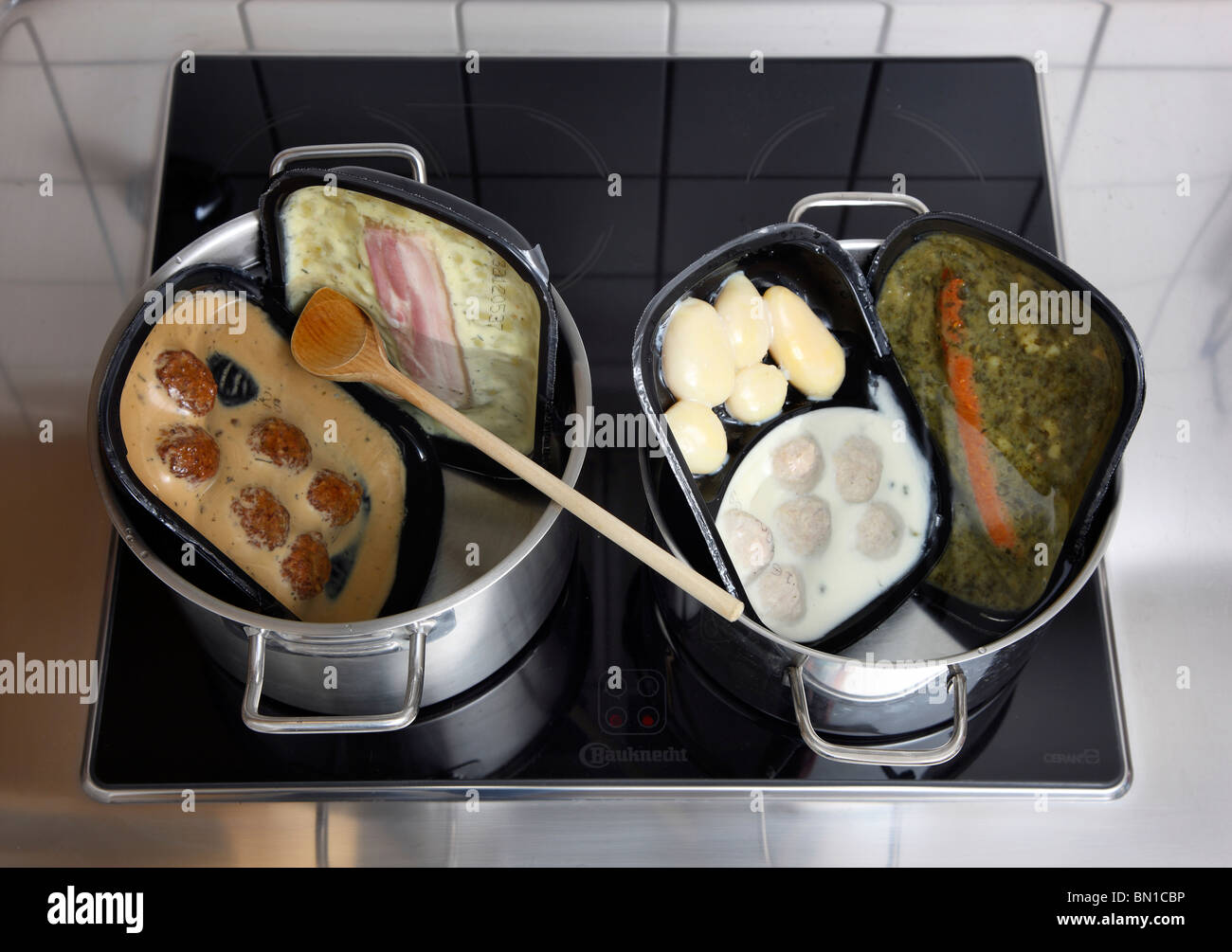 Heating of ready-to-serve meals in hot water. Convenience food products from a supermarket. different dishes, ready to eat. Stock Photo