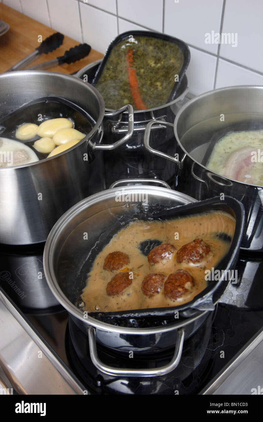 Heating of ready-to-serve meals in hot water. Convenience food products from a supermarket. different dishes, ready to eat. Stock Photo