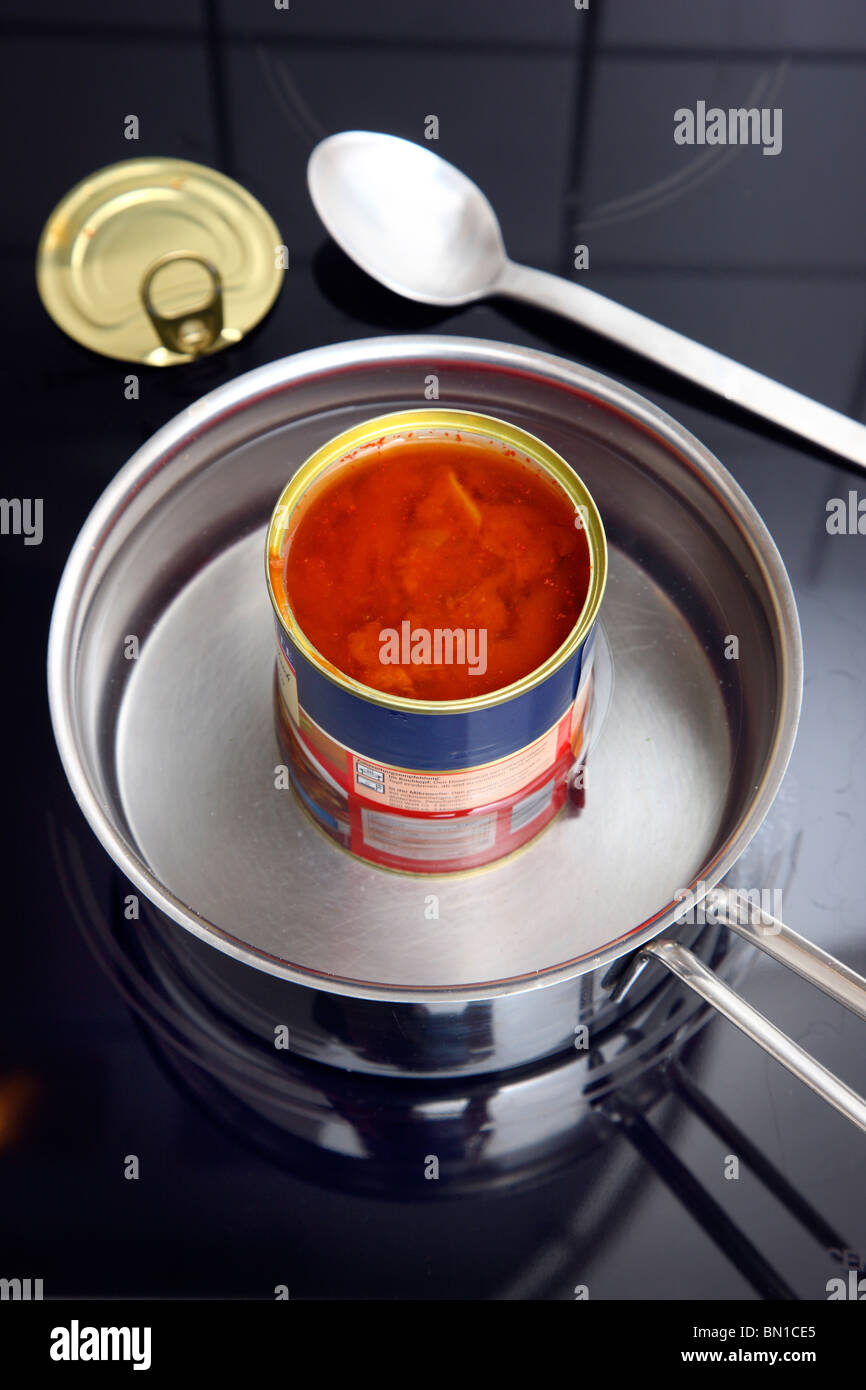 Heating of ready-to-serve meals in hot water. Soups or pasta dishes in cans. Convenience food products. Stock Photo