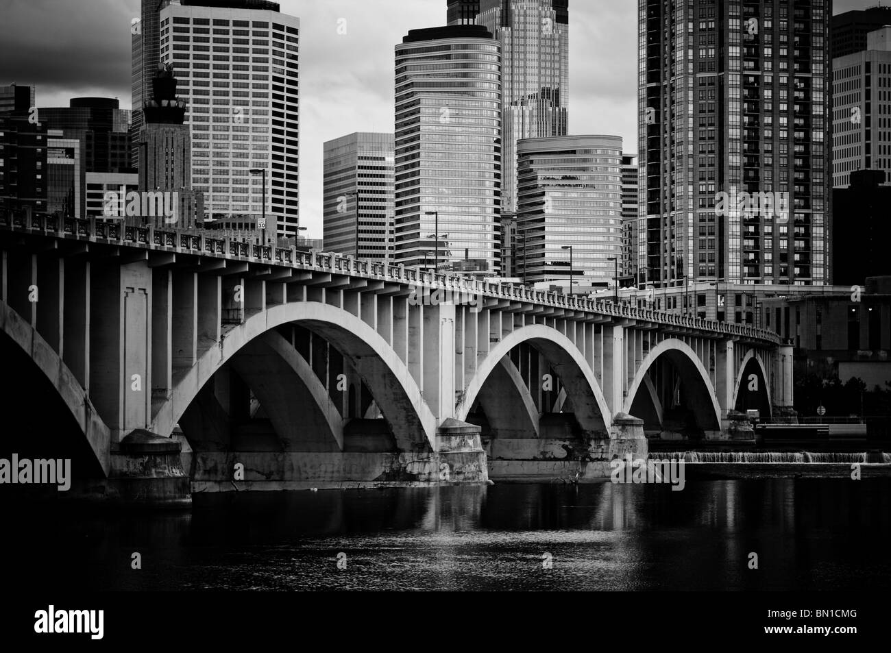 Black and white image of the Minneapolis skyline and Central Avenue bridge over the Mississippi River. Stock Photo