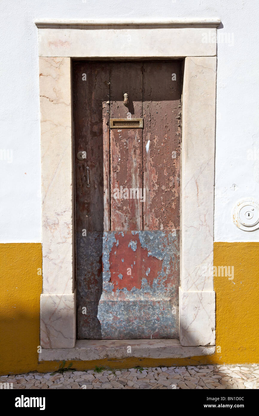 Red Rustic Faded Wood Door of Old World Europe against Yellow Wall Stock Photo