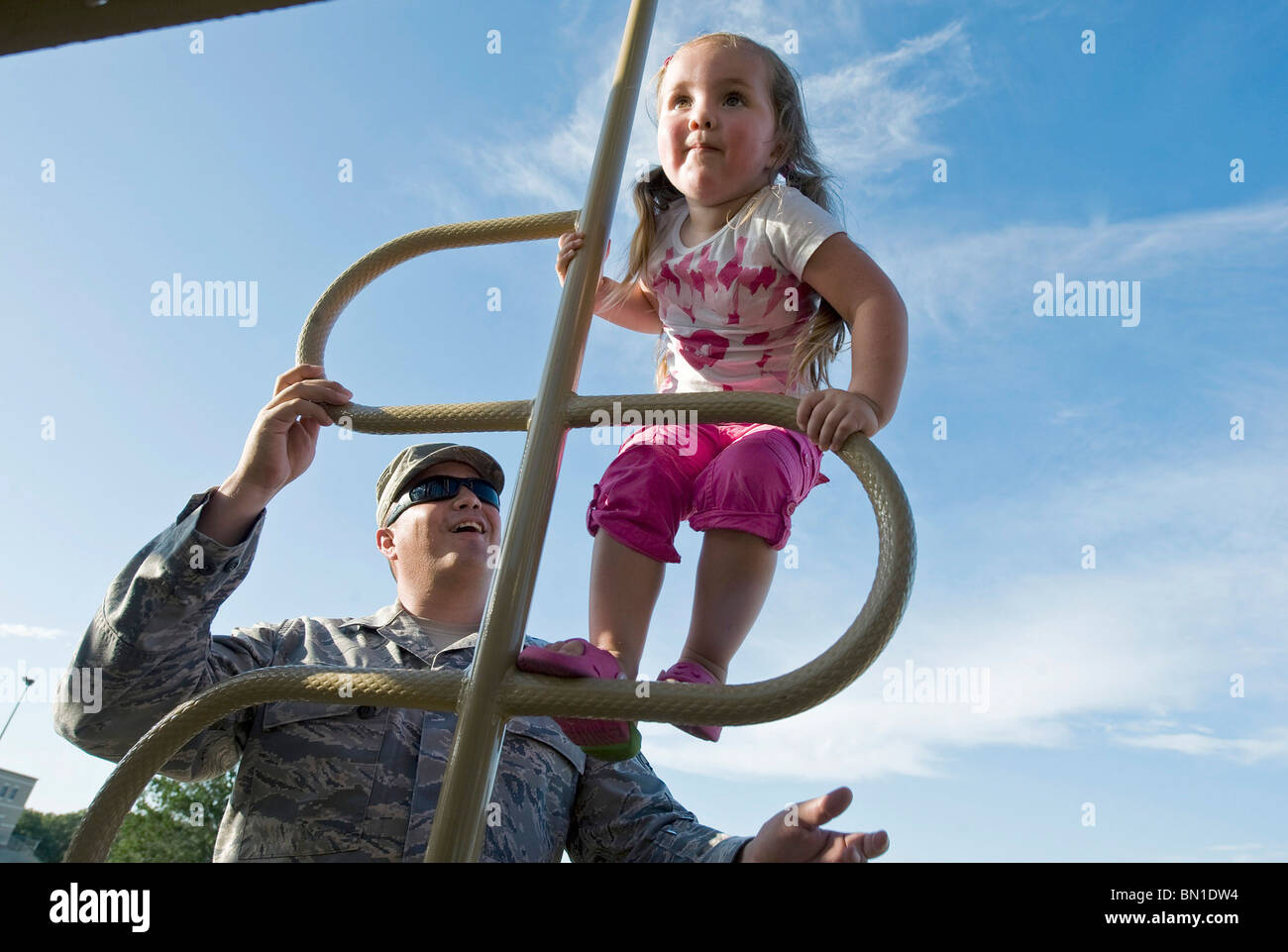 Master Sgt. Rodolfo Gamez watches over his daughter, Eva, while she climbs on a jungle gym at their neighborhood park. Stock Photo