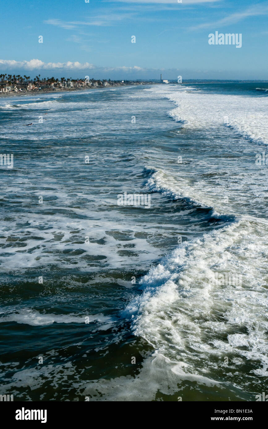 View of ocean waves from Oceanside pier with Carlsbad Encina power plant in distance, Oceanside, California, USA. - Stock Image