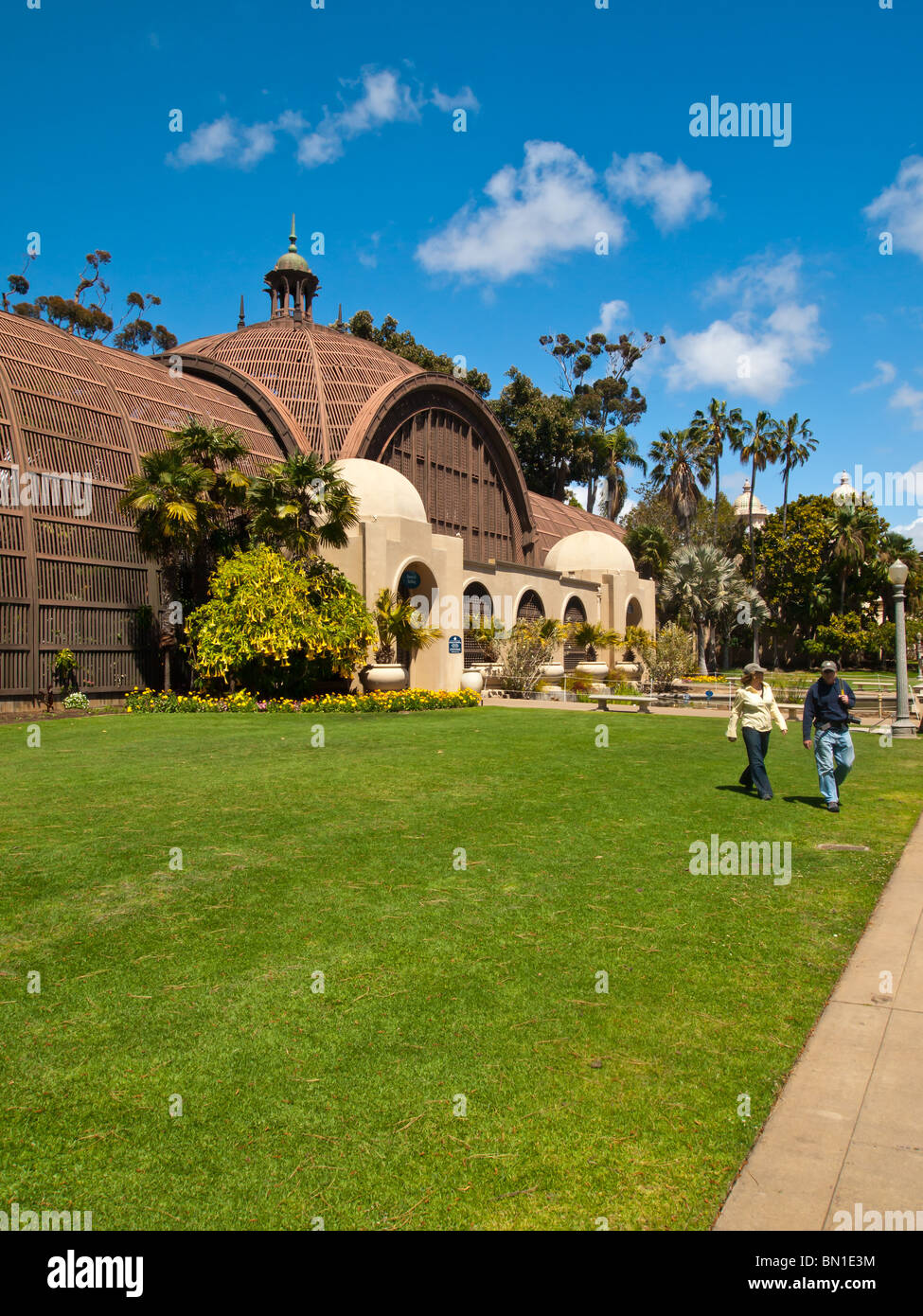 Two people walking across the lawn near the Botanical Building, Balboa Park, San Diego, California, USA. - Stock Image
