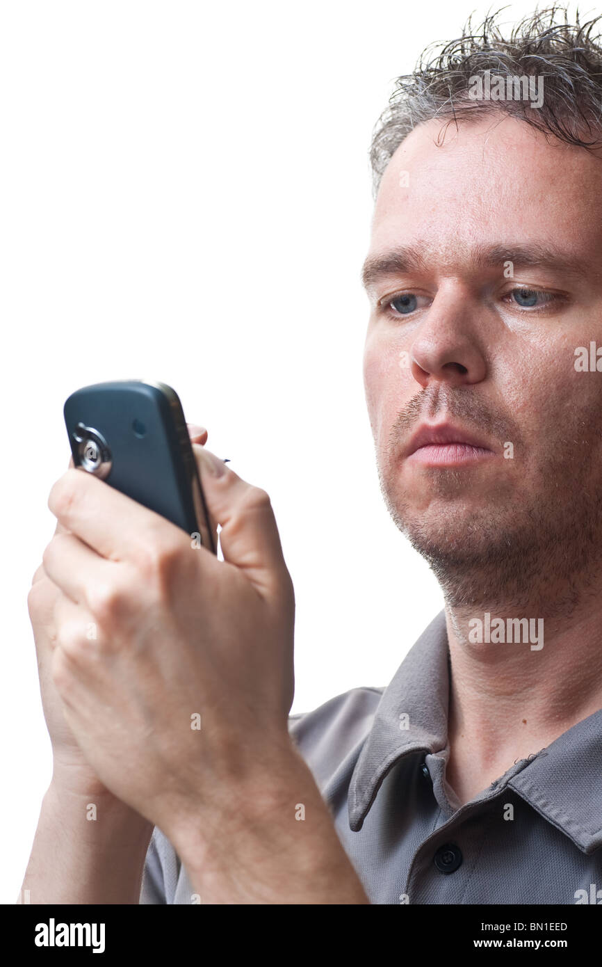 A man holding a PDA / Cel phone, looking at the screen while tapping on its screen, isolated on white. Stock Photo