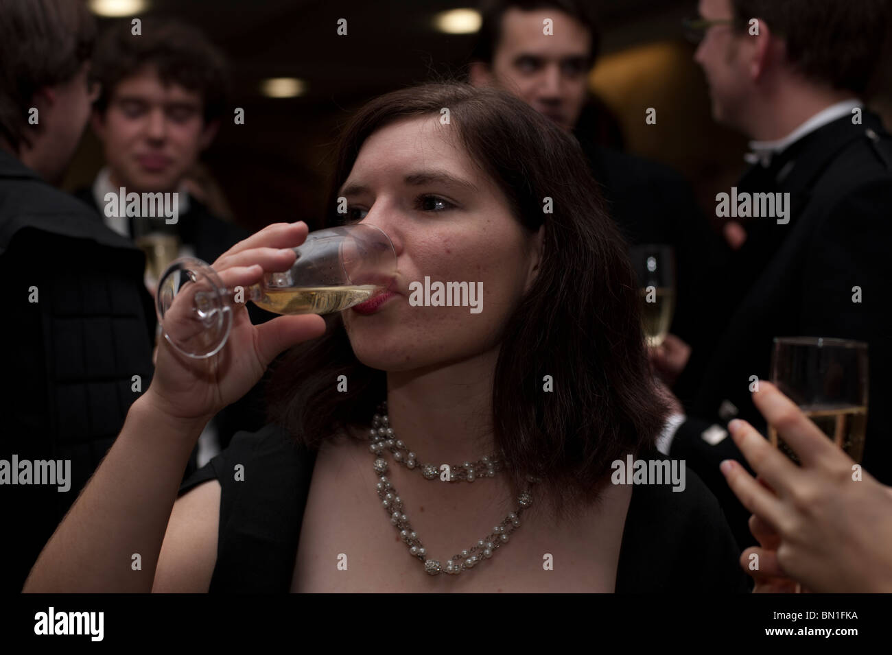 A female Oxford student drinks champagne at a formal event at an Oxford