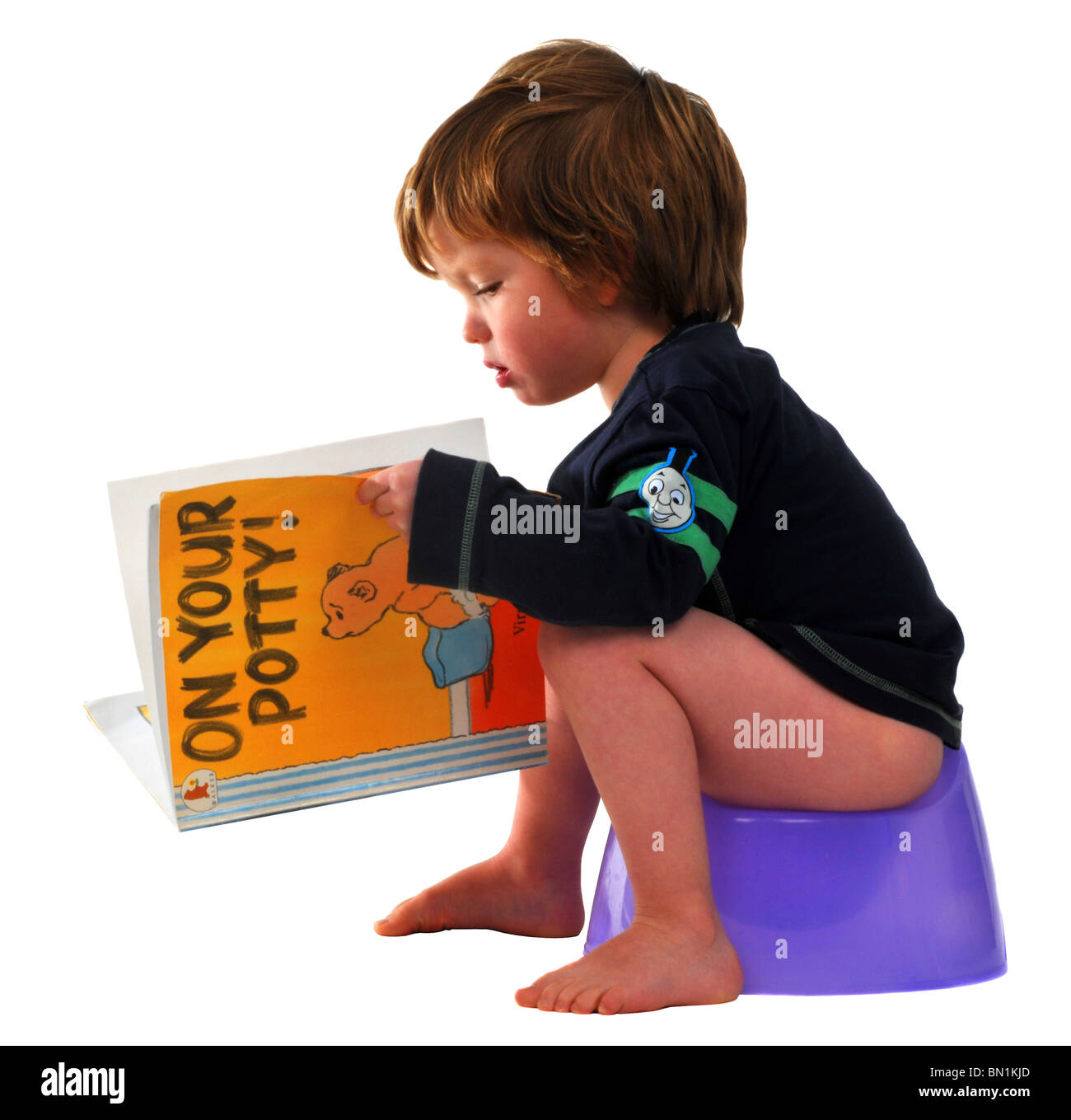 “Potty training” child sitting on a potty reading Stock Photo Alamy