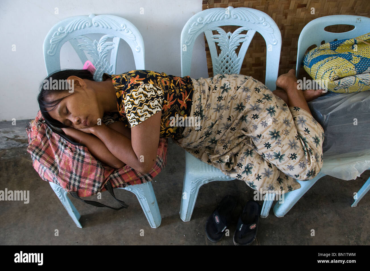 Cyclone Nargis survivor sleeps on plastic chairs in Khunkthan township of Yangon, Myanmar, Burma, Stock Photo