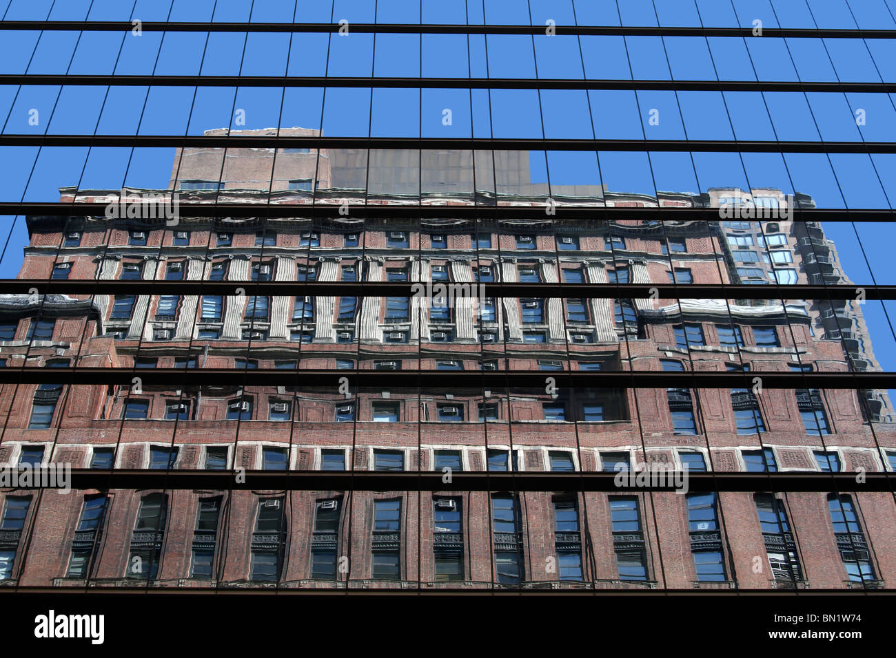 Brick building looks distorted from a reflection of contemporary glass building. Stock Photo