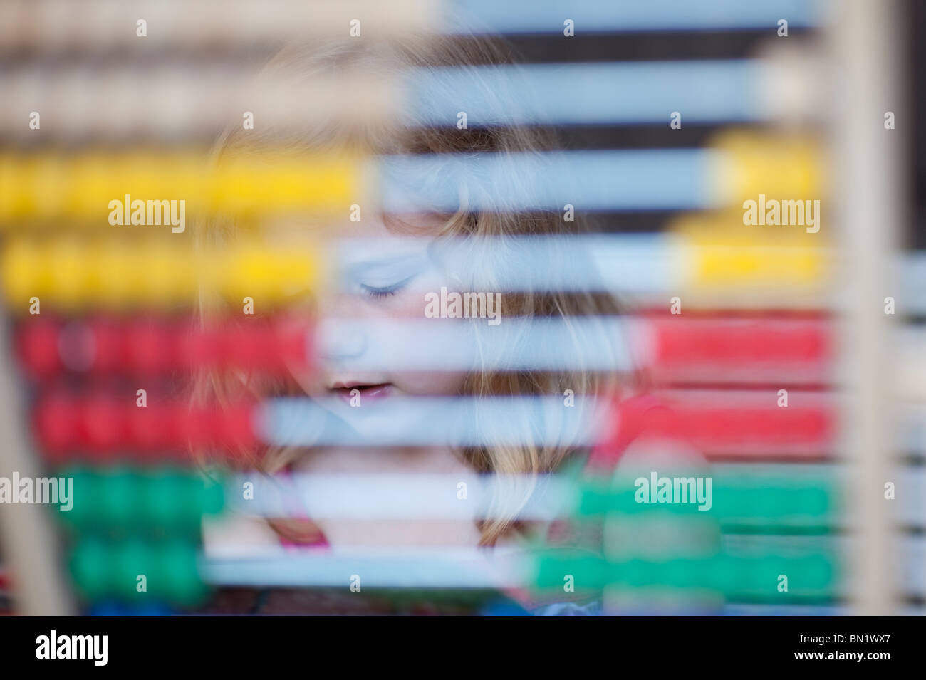 Primary aged girl seen photographed through an abacus. Stock Photo