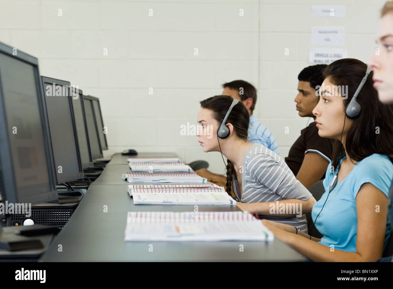 Students studying in computer lab, one leaning forward to see screen