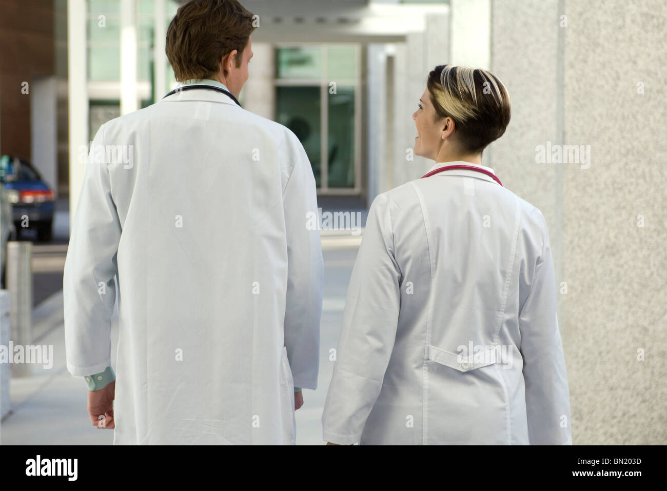 Doctors chatting and walking together along hospital corridor, rear view Stock Photo
