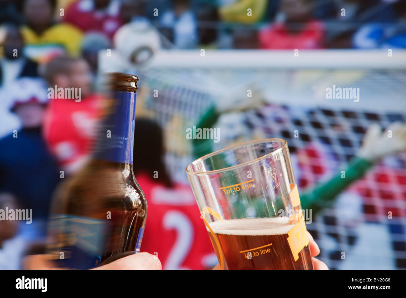 Watching world cup football match on pub tv screen with bottle of beer and glass of beer in foreground Stock Photo