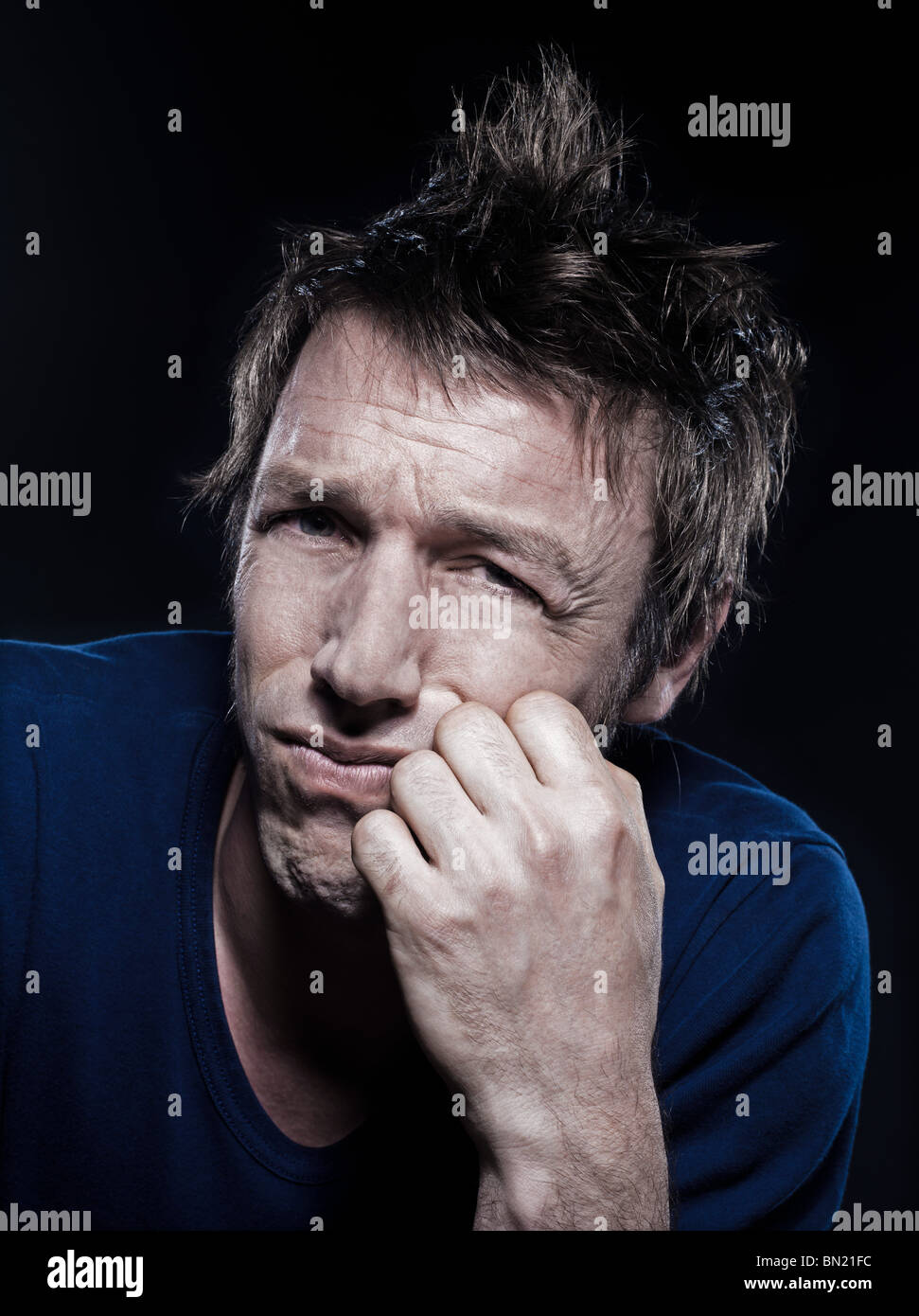 studio portrait on black background of a funny expressive caucasian man puckering sad sullen Stock Photo