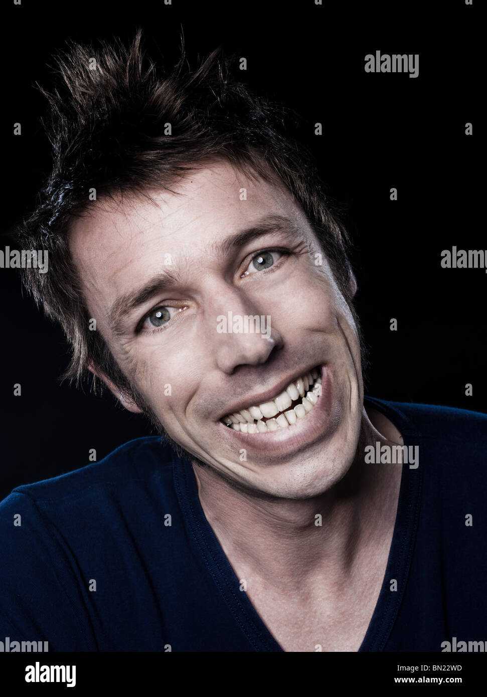 studio portrait on black background of a funny expressive caucasian man grimacing toothy smile Stock Photo