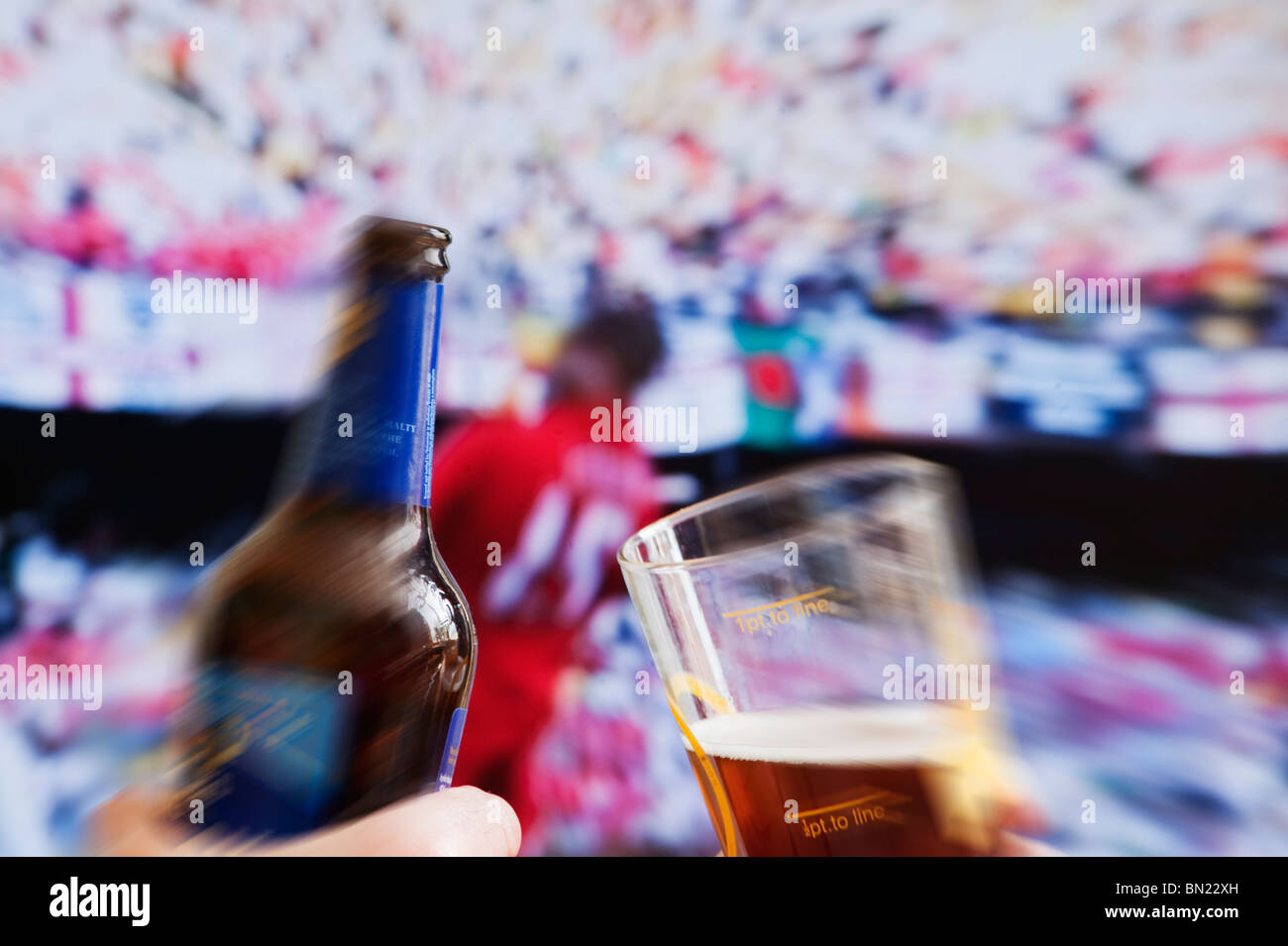 Watching world cup football match on pub tv screen with bottle of beer in foreground Stock Photo