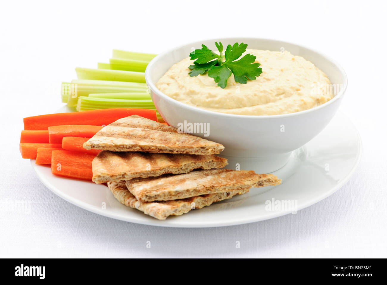 Healthy snack of hummus dip with pita bread slices and vegetables Stock