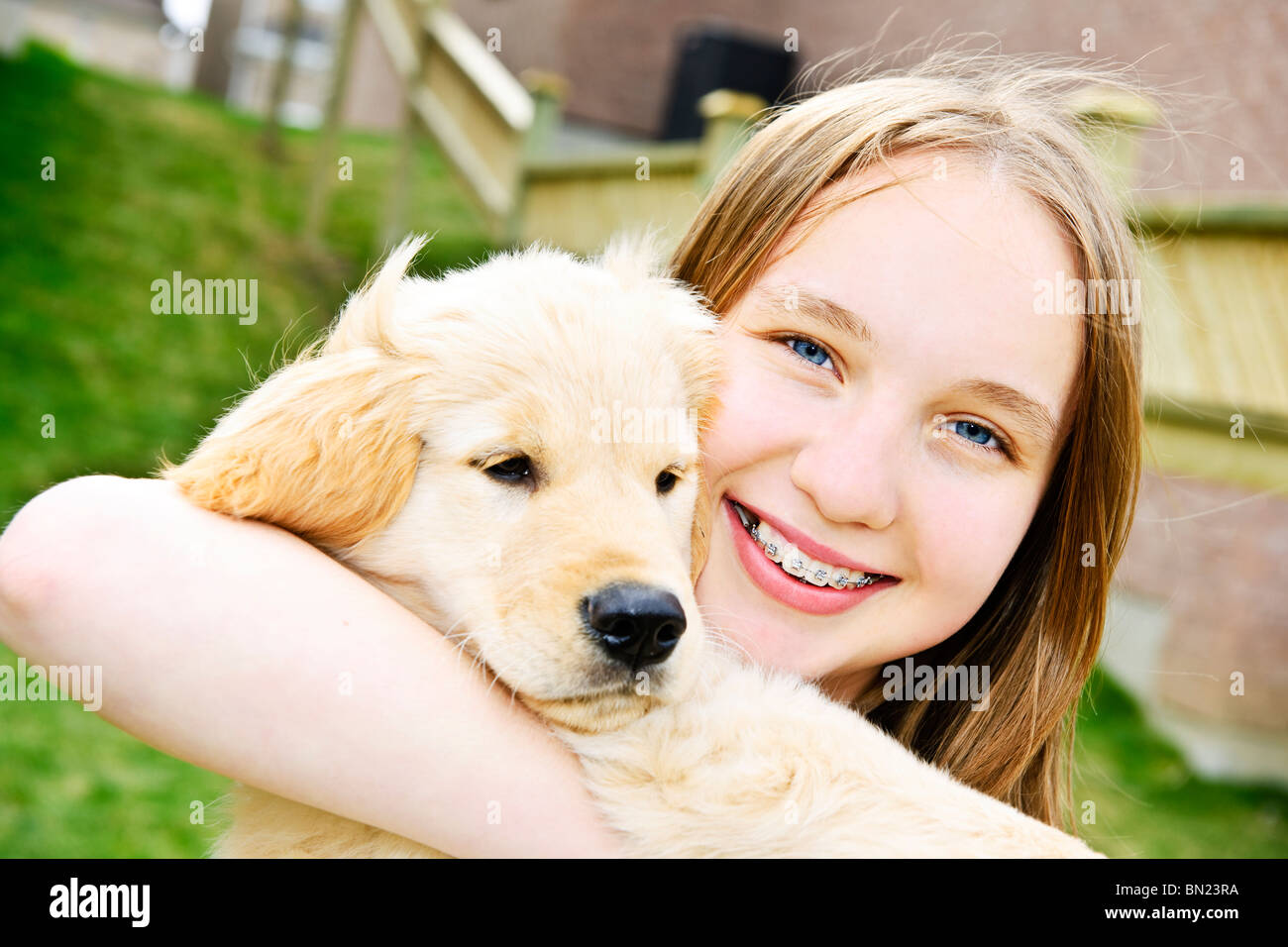Portrait of smiling teenage girl holding golden retriever puppy Stock