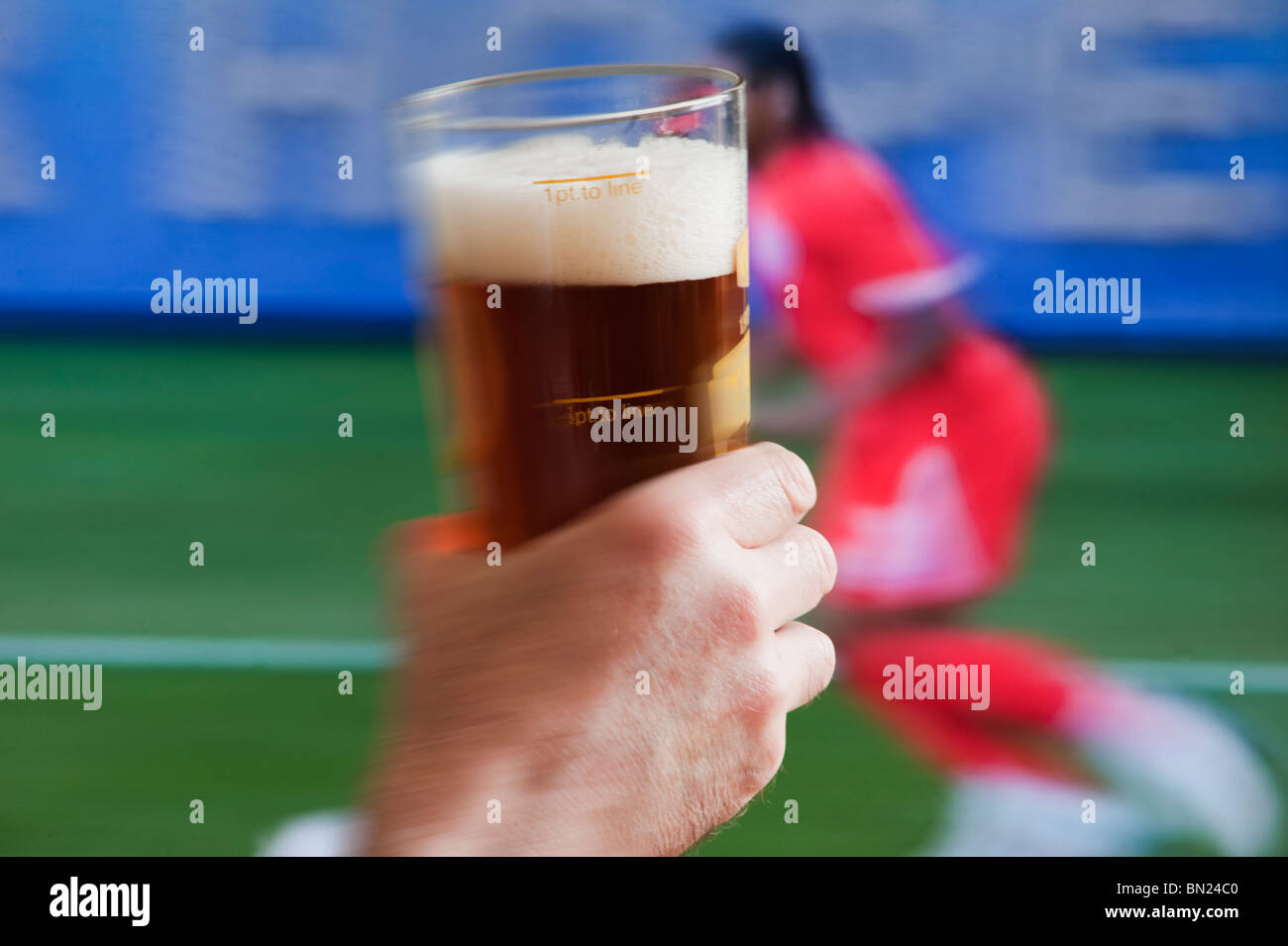 Watching world cup football match on pub tv screen with pint glass of beer in foreground Stock Photo