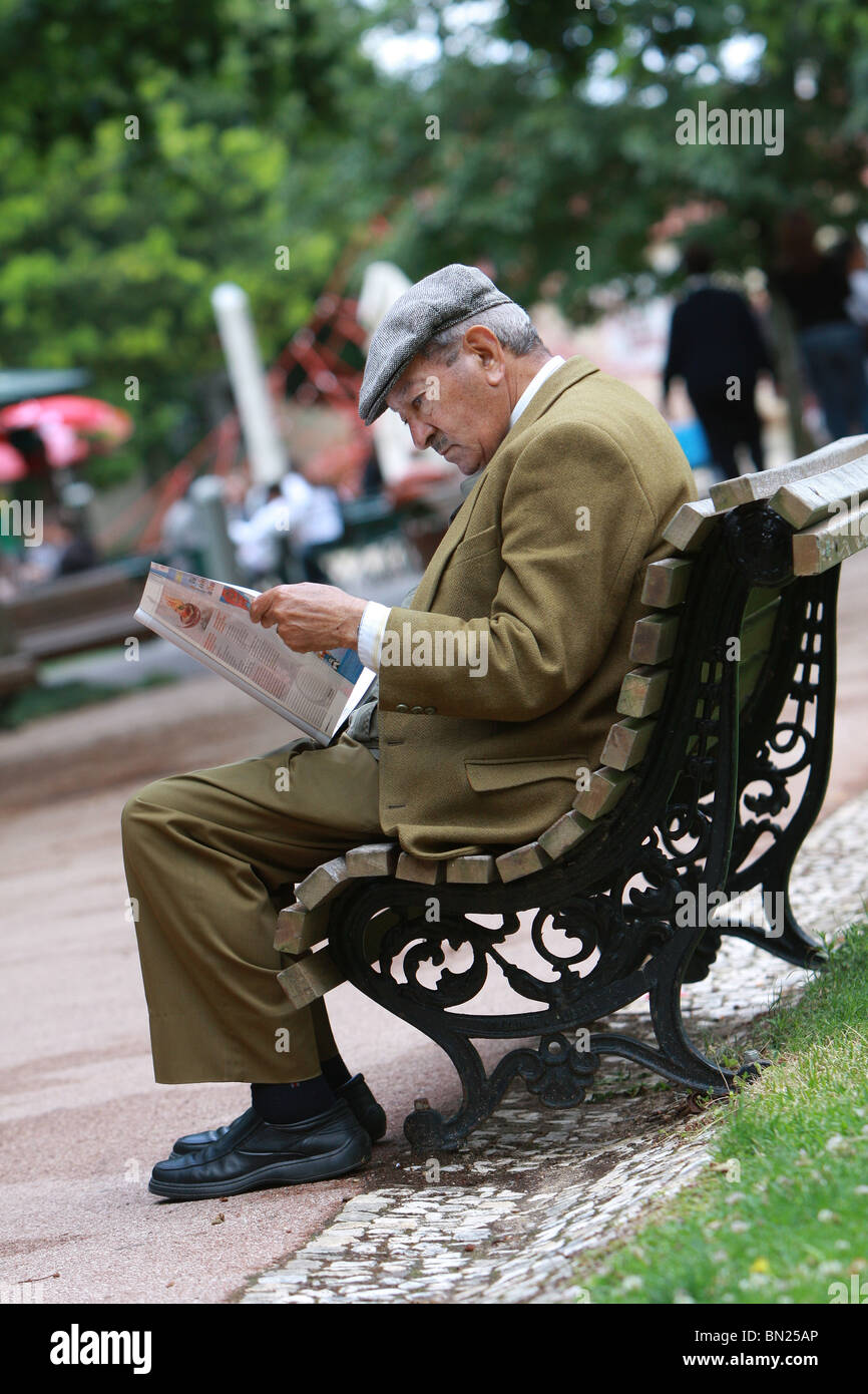 Man sitting on a bench reading a newspaper Stock Photo - Alamy