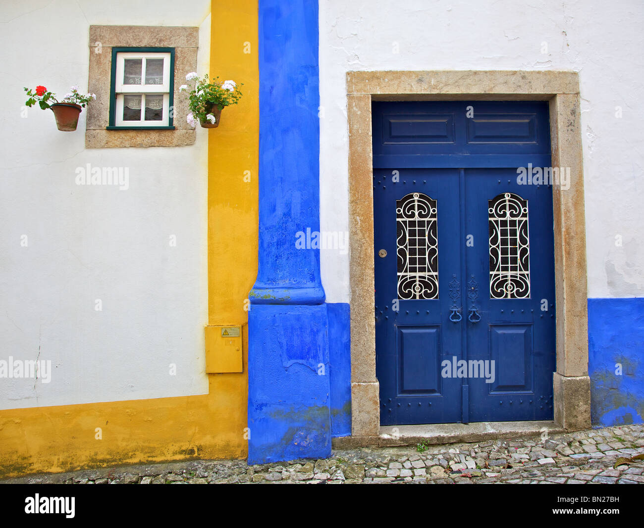 Rustic Blue Wood Door against a Blue & Yellow Wall in a Medieval Walled Village Stock Photo