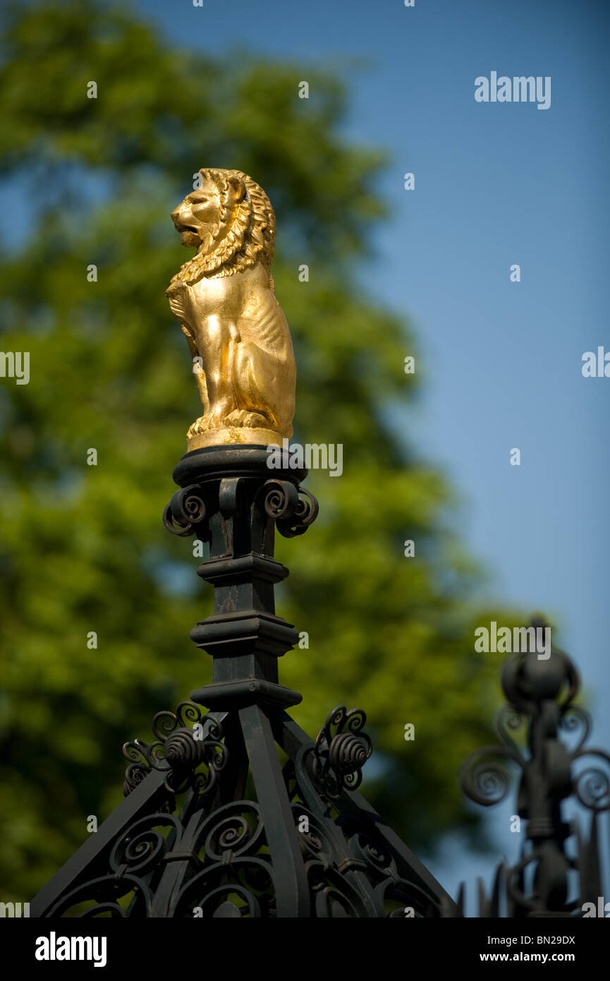 Close up of a small Golden Lion statue on top of the gates outside the