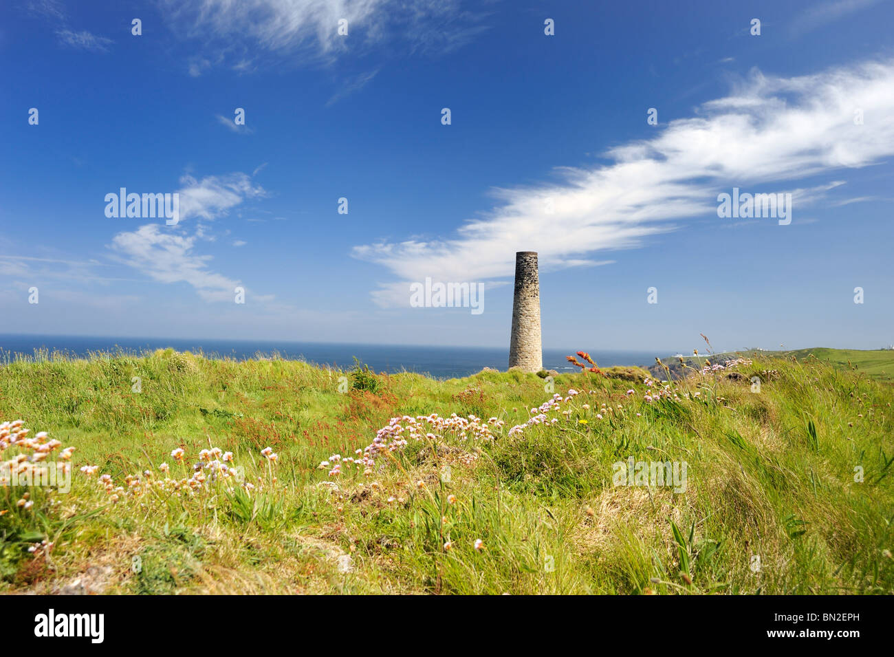 An old chimney of a Cornish tin mine sits in the grass on the cliff top Stock Photo