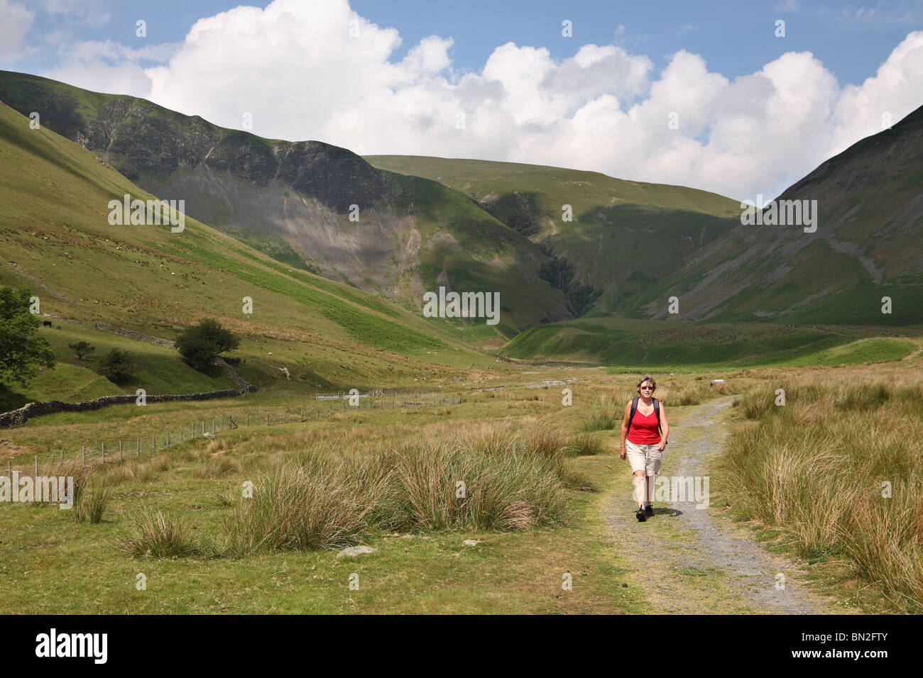 A mature woman walking in the Howgill fells with Cautley Spout waterfall in the background, near Sedbergh, Cumbria, England, UK Stock Photo