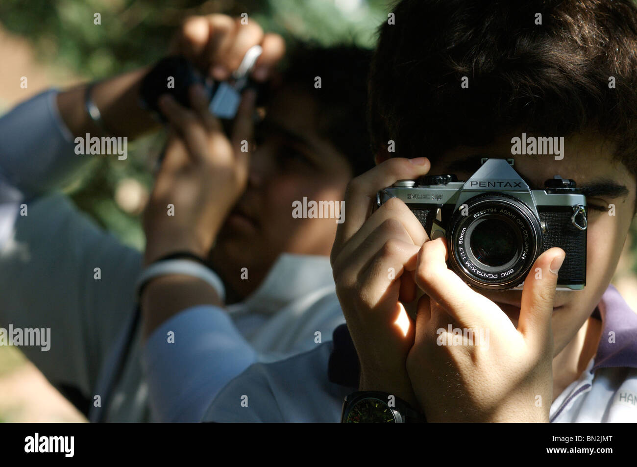 Two Asian boys taking photographs with manual SLR cameras in the sunlight Stock Photo