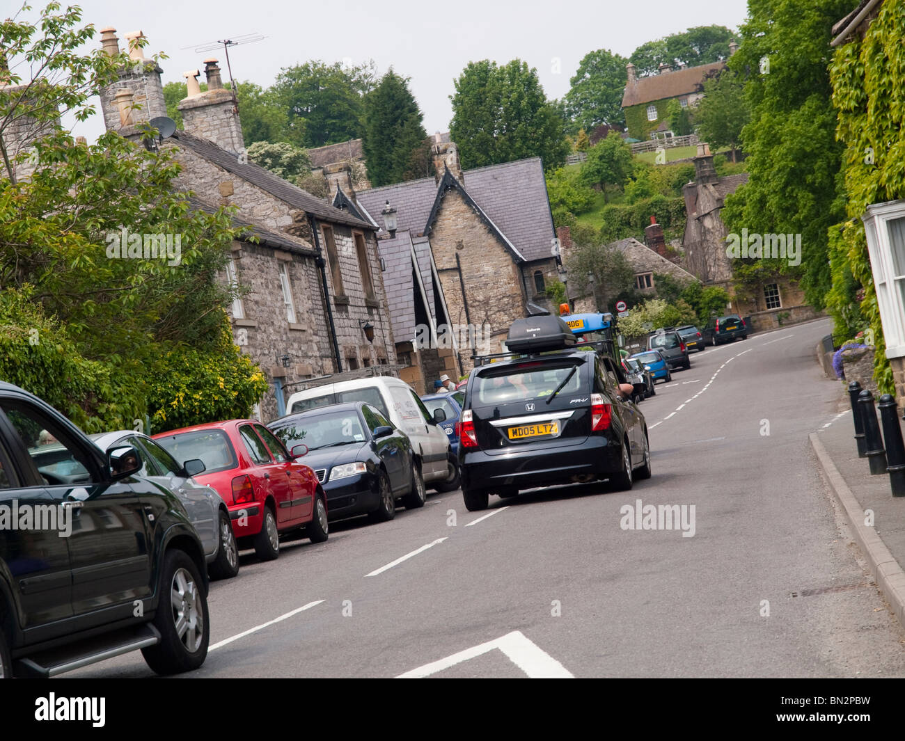 Cars driving through a village in the Peak District, Derbyshire England