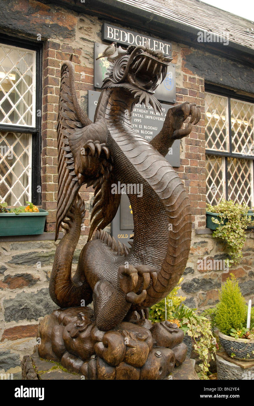 Large carving of the welsh dragon in Beddgelert, Snowdonia, Wales, with a sparrow sitting on its head Stock Photo