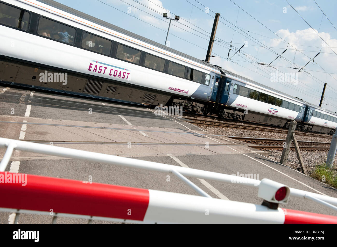 East Coast high speed passenger train travelling at speed through a level crossing on the east coast main line in England. Stock Photo