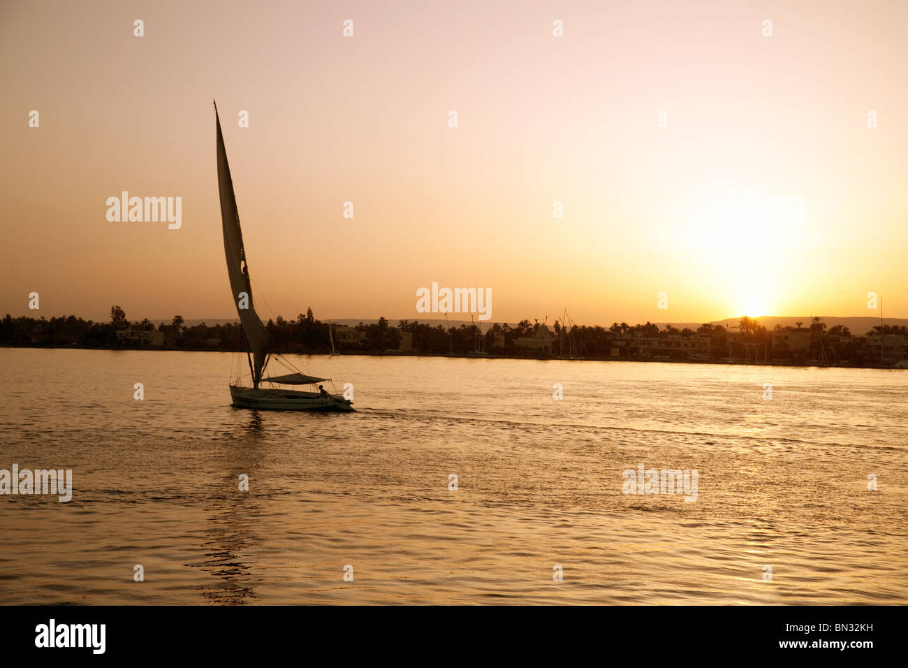 A felucca sails past at sunset, the River Nile at Luxor, Egypt Stock Photo