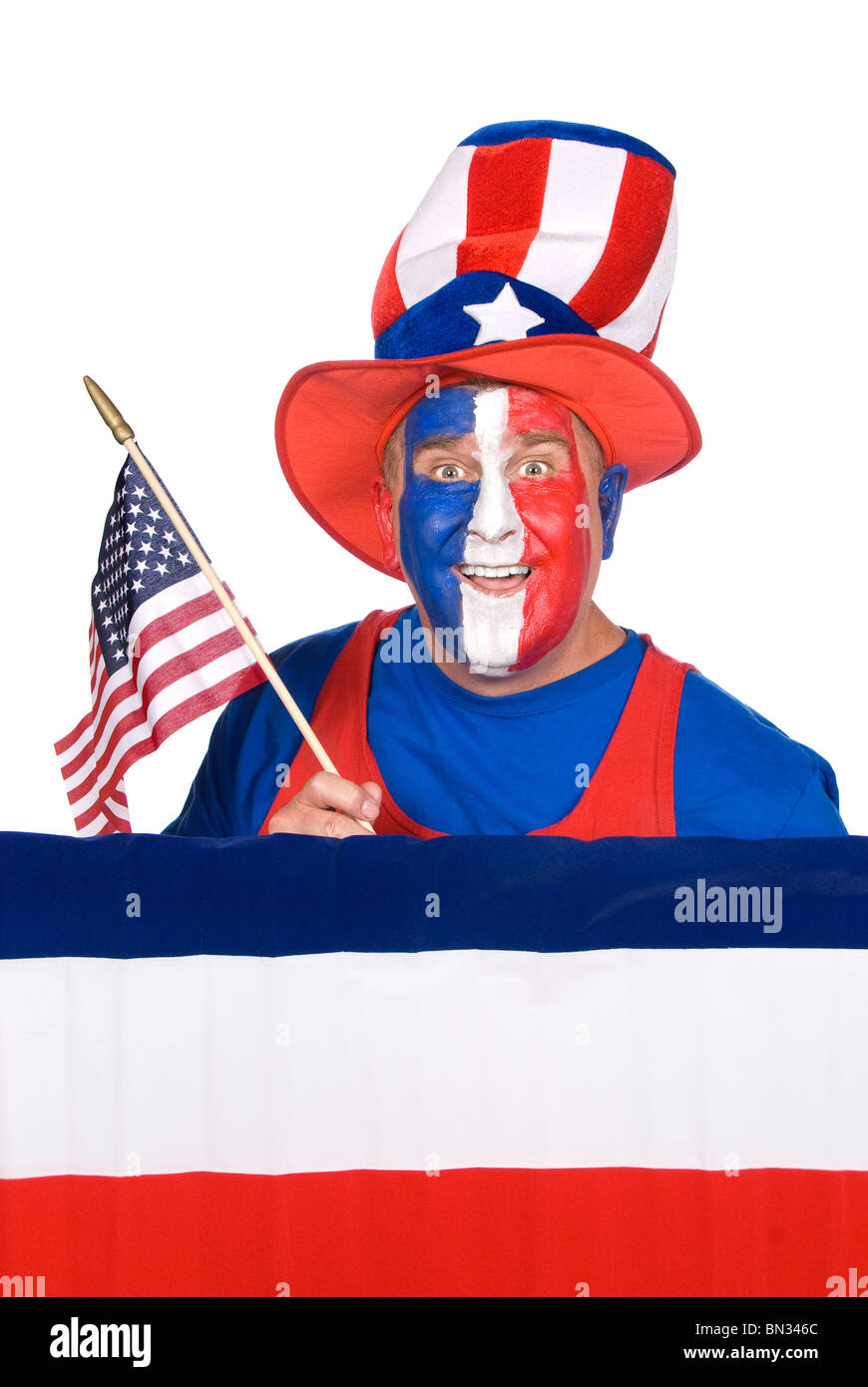 A patriotic man with red, white and blue face paint holds up an American flag. Stock Photo