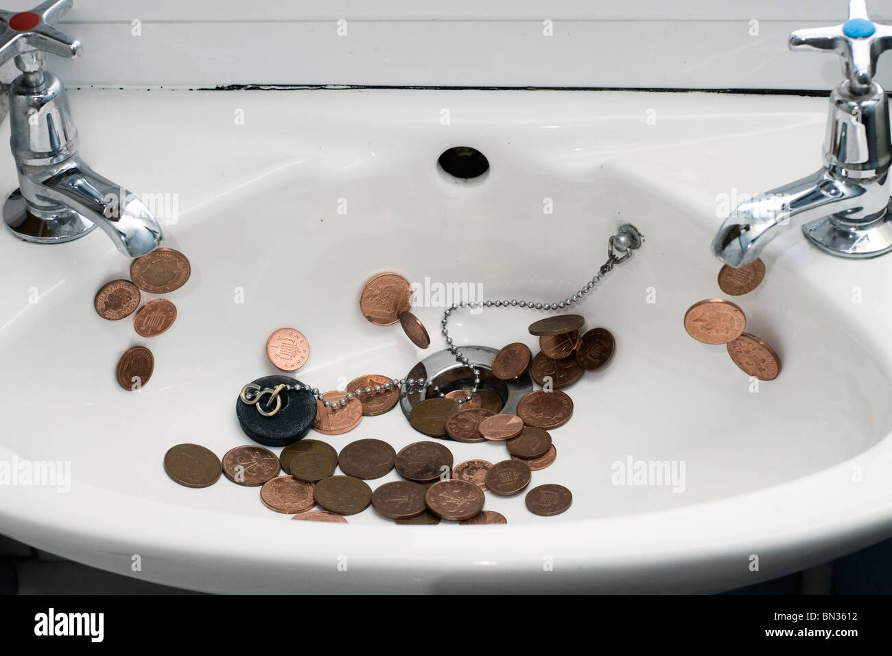 A bathroom sink with pennies pouring from the taps Stock Photo Alamy